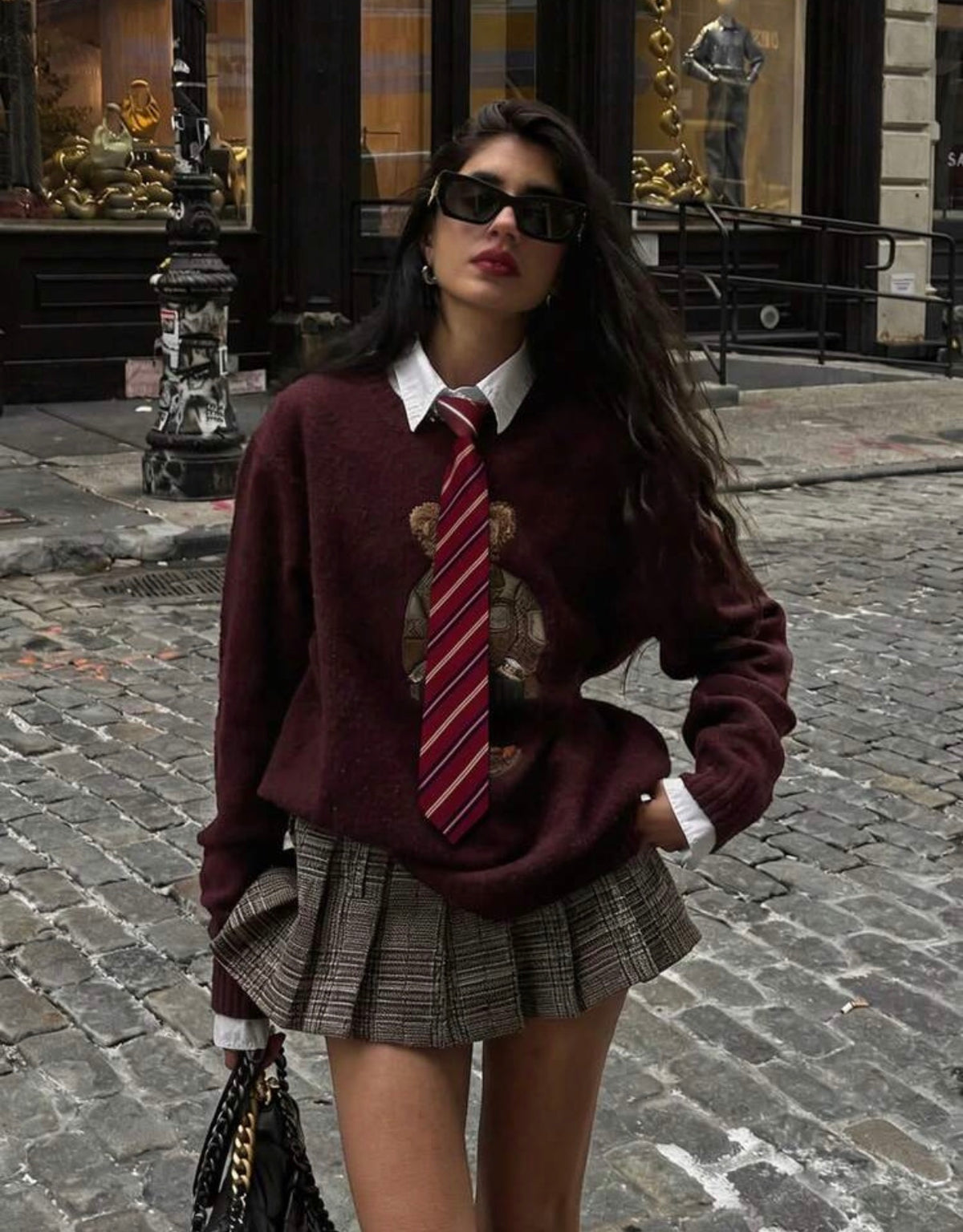 Cravate bordeaux rayée portée avec pull bordeaux et jupe plissée