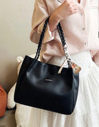 Sac cabas noir porté à l'épaule avec poignées tressées